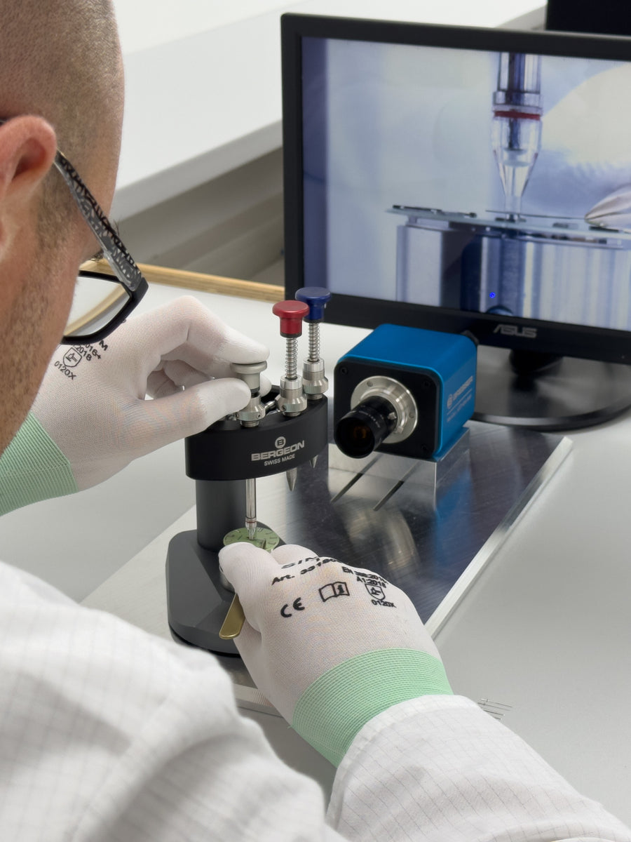 A watchmaker setting hands with a hand-setting press.